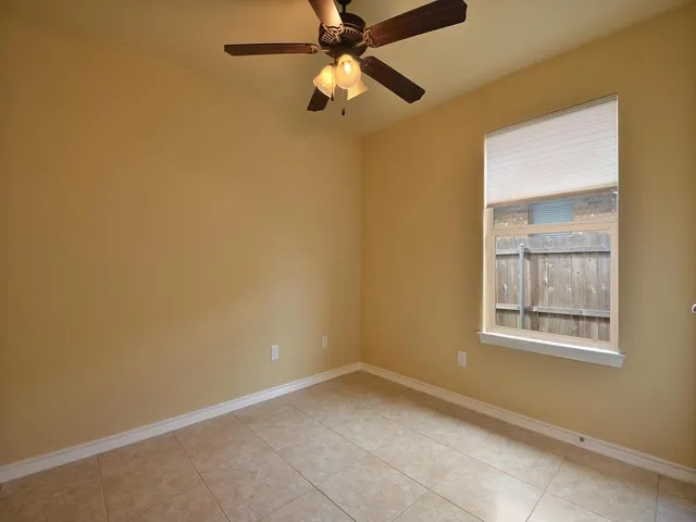an empty room with a window and a fan