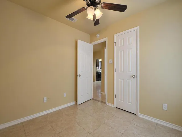 a view of an empty room and chandelier fan