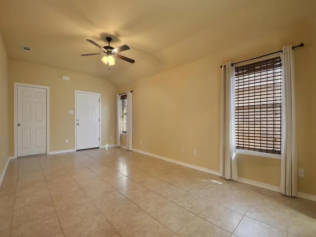 a view of an empty room with a ceiling fan and window
