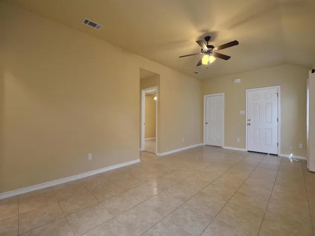 a view of an empty room and window a ceiling fan