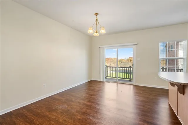 an empty room with wooden floor chandelier and windows