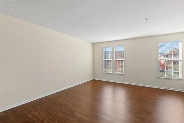 a view of an empty room with wooden floor and windows