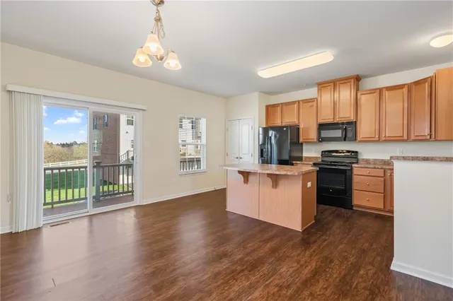 a kitchen with granite countertop a stove top oven a sink with wooden floors and cabinets