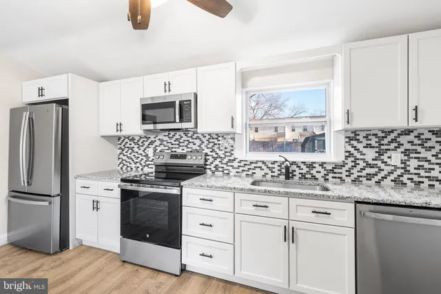 a kitchen with granite countertop white cabinets and stainless steel appliances