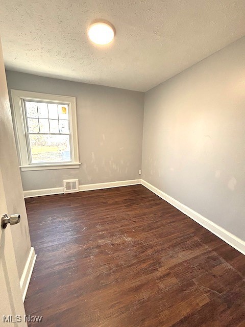 932 Nela View Road Cleveland Heights, OH 44112 - Photo 2 of 8 Empty room with dark wood-style floors, baseboards, visible vents, and a textured ceiling