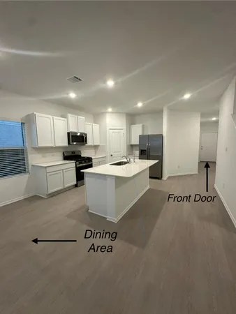 a large white kitchen with stainless steel appliances kitchen island a stove a sink a refrigerator and white cabinets
