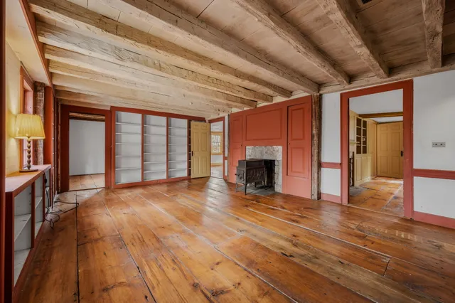 a view of an empty room with wooden floor and furniture