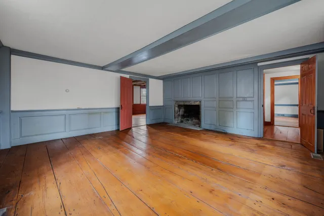 an empty room with wooden floor fireplace and windows