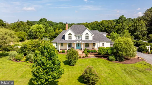 a view of a house with a big yard and large trees