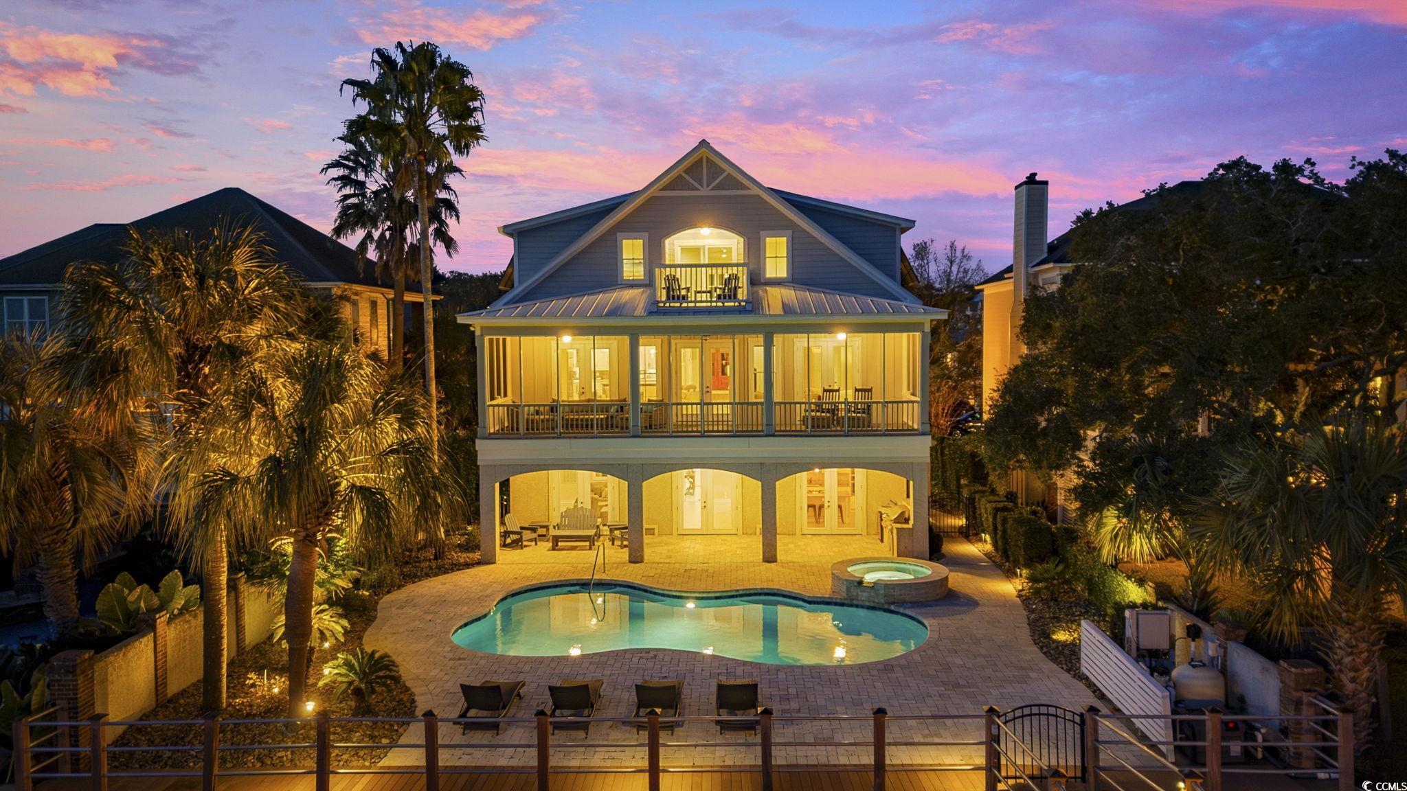 636 North Creekside Drive Murrells Inlet, SC 29576 - Photo 3 of 40 Back of property at dusk featuring a patio area, a pool with connected hot tub, a fenced backyard, a balcony, and a metal roof