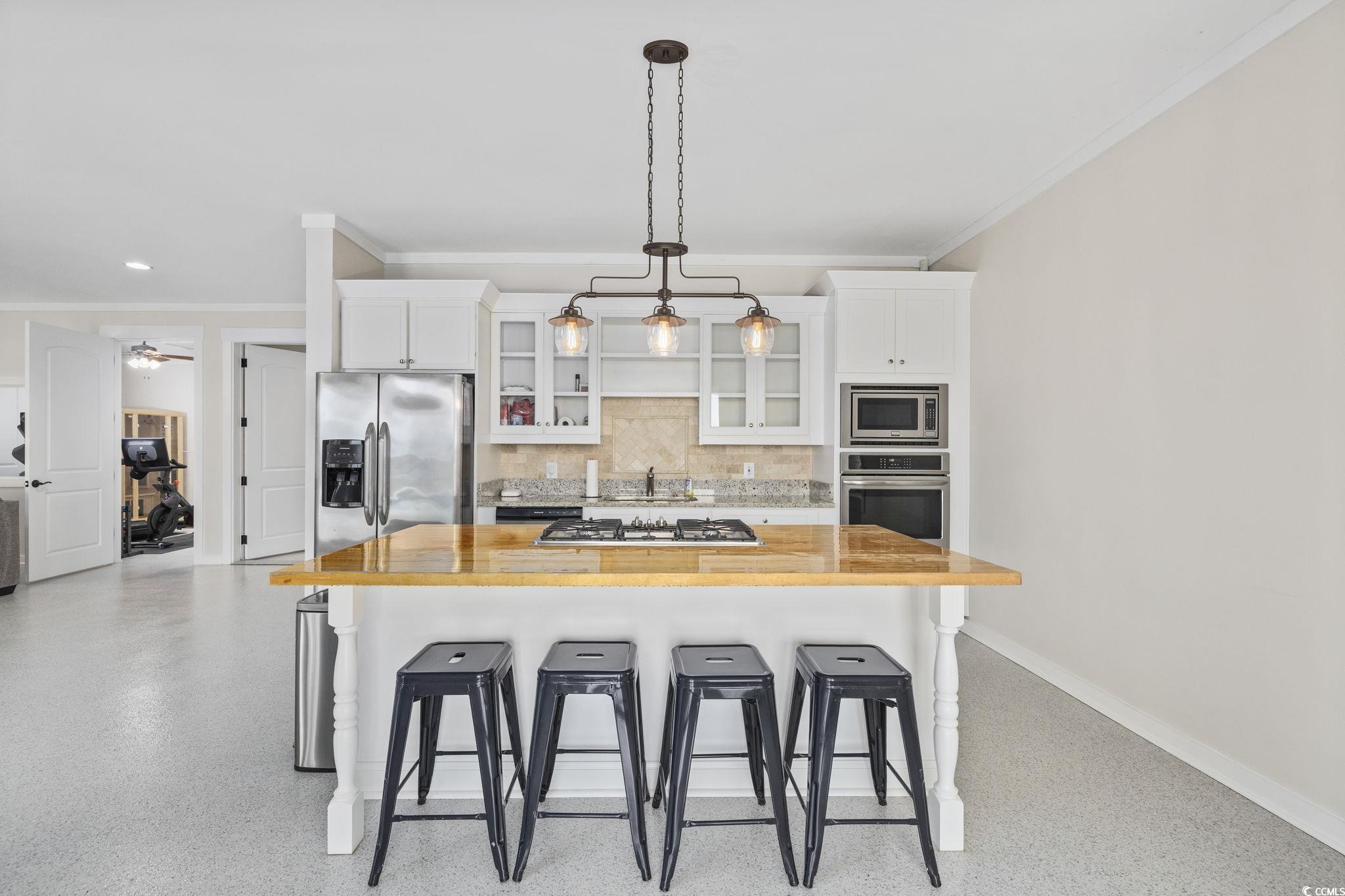 636 North Creekside Drive Murrells Inlet, SC 29576 - Photo 31 of 40 Kitchen featuring white cabinets, a kitchen breakfast bar, glass insert cabinets, ornamental molding, and a large island