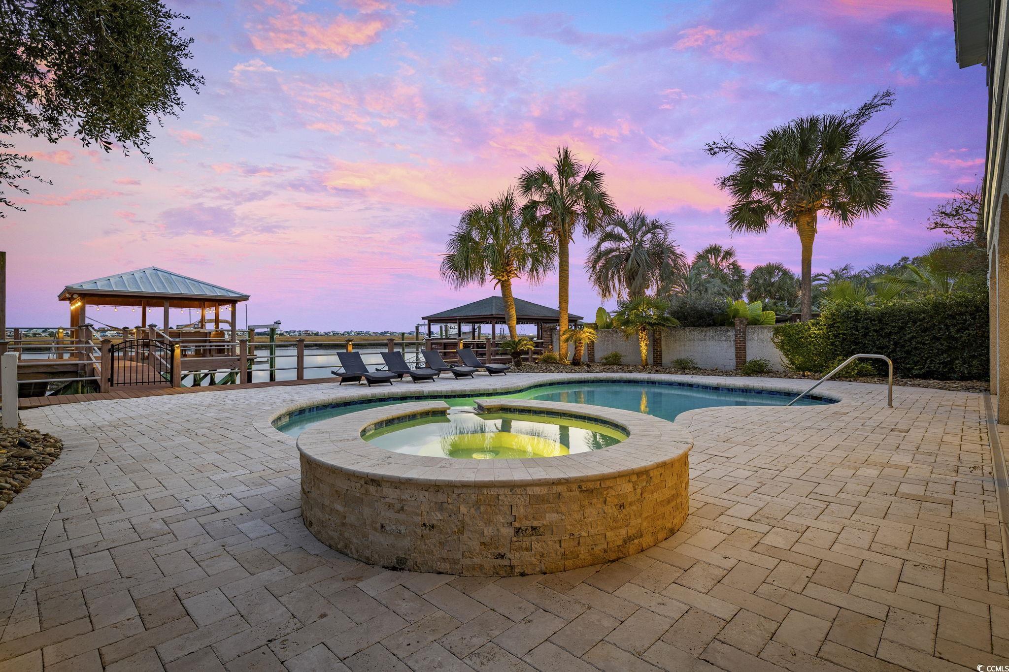 636 North Creekside Drive Murrells Inlet, SC 29576 - Photo 36 of 40 Pool at dusk with a patio area, a fenced backyard, and a pool with connected hot tub