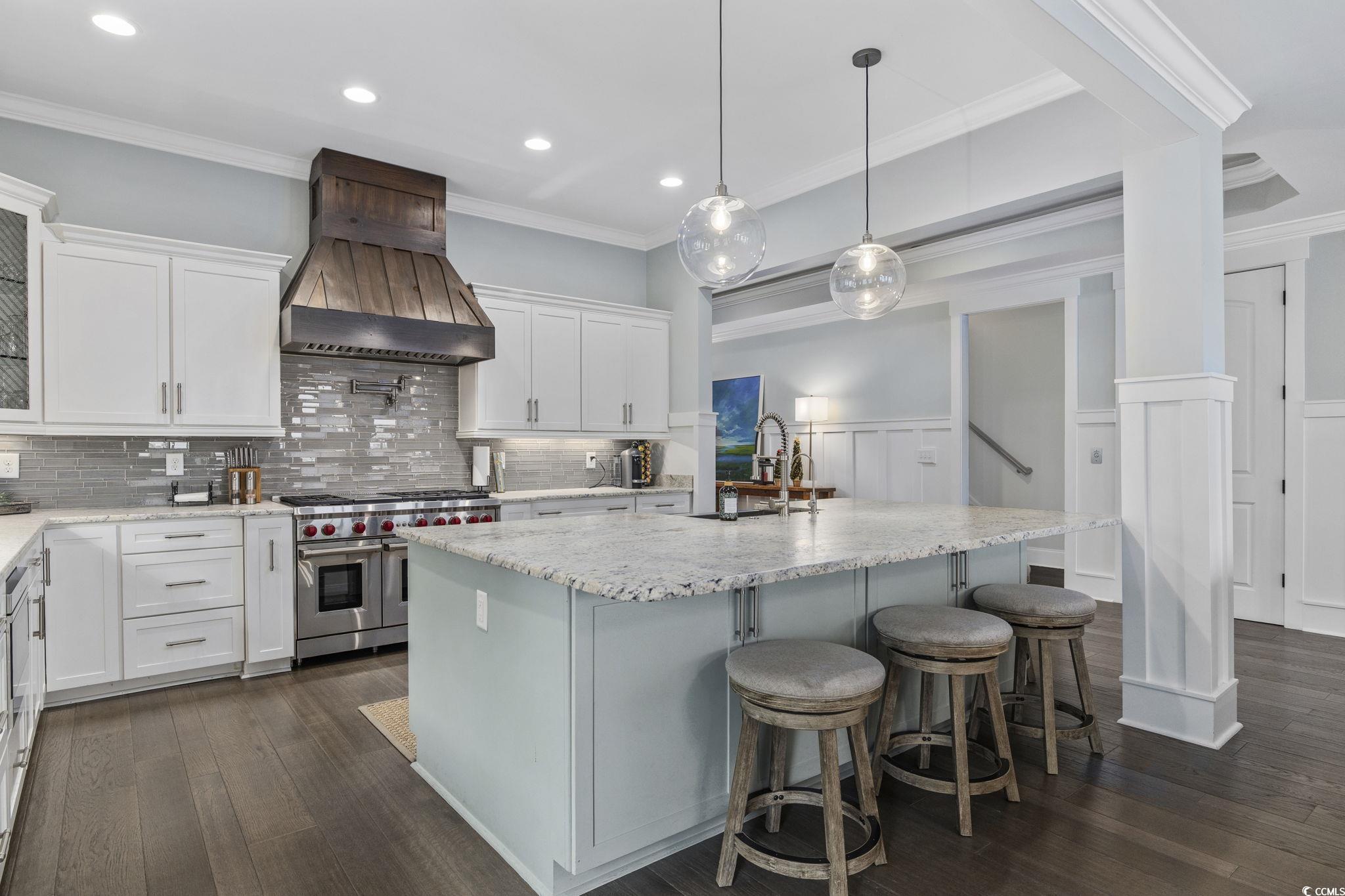 636 North Creekside Drive Murrells Inlet, SC 29576 - Photo 8 of 40 Kitchen with white cabinets, a wainscoted wall, double oven range, light stone counters, and custom exhaust hood