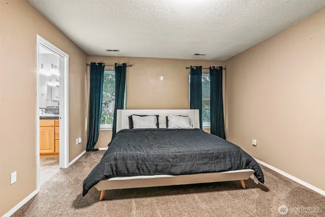 a bedroom with a large bed and dresser with mirror
