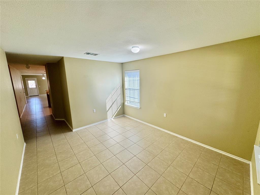 7812 Duber Lane Austin, TX 78747 - Photo 5 of 15 Spacious living area featuring neutral wall tones, square tile flooring, a window with blinds, and white trim accents