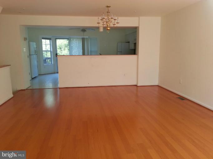 6174 Silver Arrows Way Columbia, MD 21045 - Photo 22 of 25 an empty room with wooden floor and chandelier