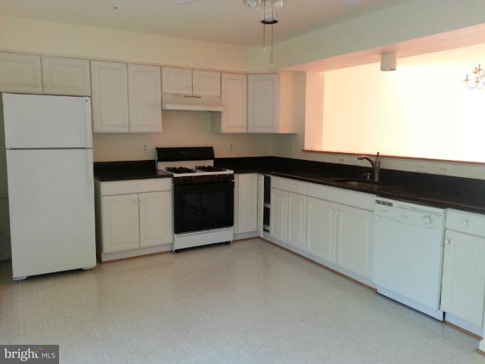 6174 Silver Arrows Way Columbia, MD 21045 - Photo 4 of 25 a kitchen with granite countertop white cabinets and white appliances