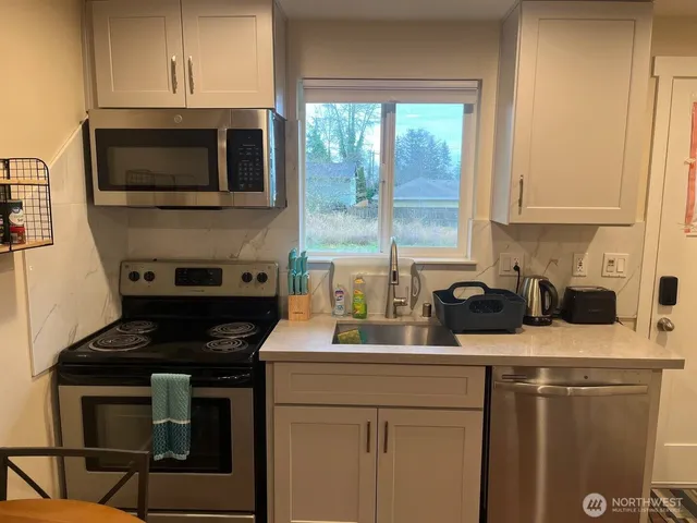 a kitchen with stainless steel appliances a stove a sink a microwave a refrigerator and cabinets