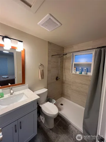a bathroom with a bathtub shower sink vanity mirror and toilet