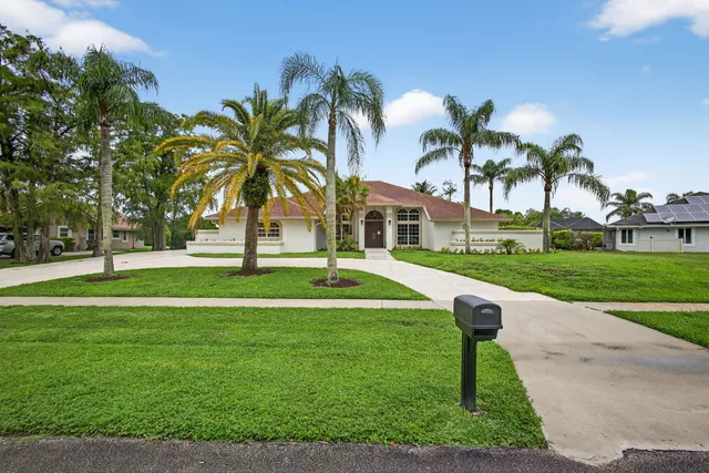 a front view of a house with a yard and palm trees