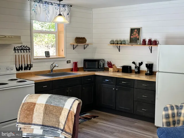 a kitchen with stainless steel appliances granite countertop a stove a sink a refrigerator wooden floor and cabinets