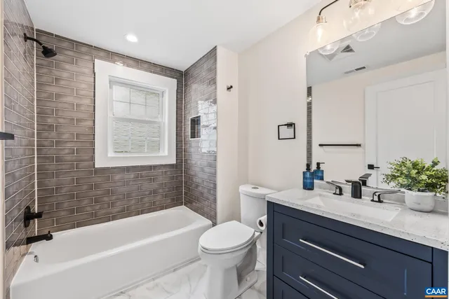 a bathroom with a sink a toilet a mirror a vanity a bathtub and shower