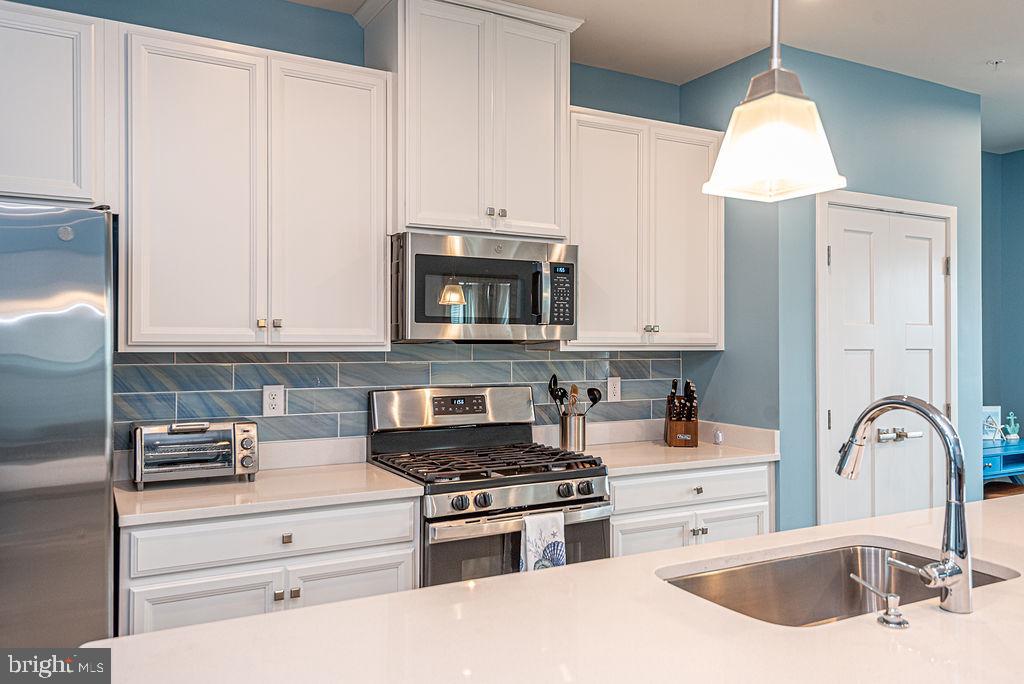 12461 Coastal Marsh Drive, Unit 708 Berlin, MD 21811 - Photo 17 of 56 a kitchen with granite countertop a stove a sink and a microwave
