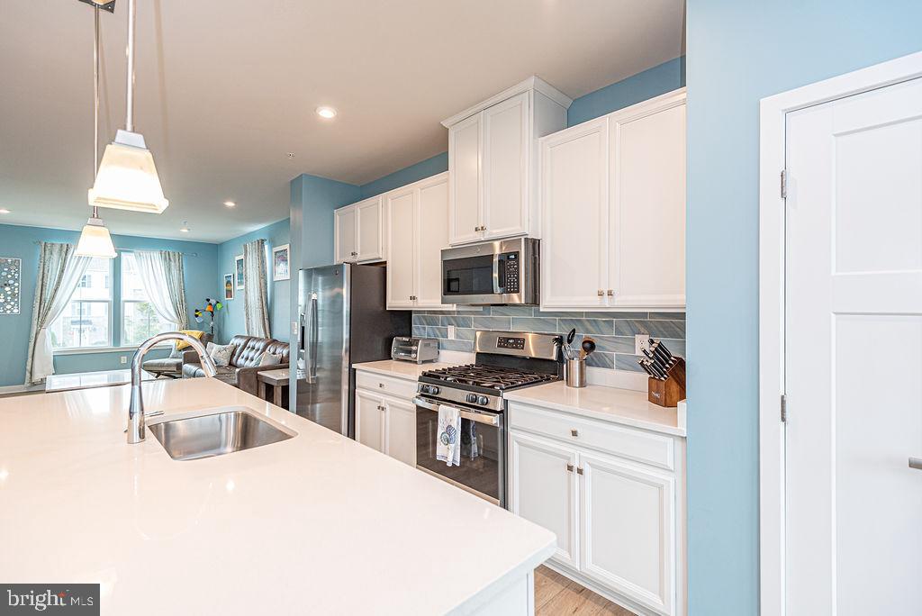12461 Coastal Marsh Drive, Unit 708 Berlin, MD 21811 - Photo 22 of 56 a kitchen with stainless steel appliances a sink a stove a microwave a center island and cabinets