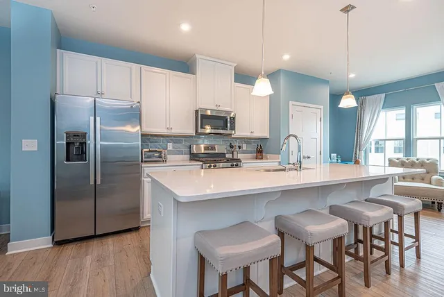 a kitchen with stainless steel appliances a sink a stove a refrigerator with a dining table and chairs