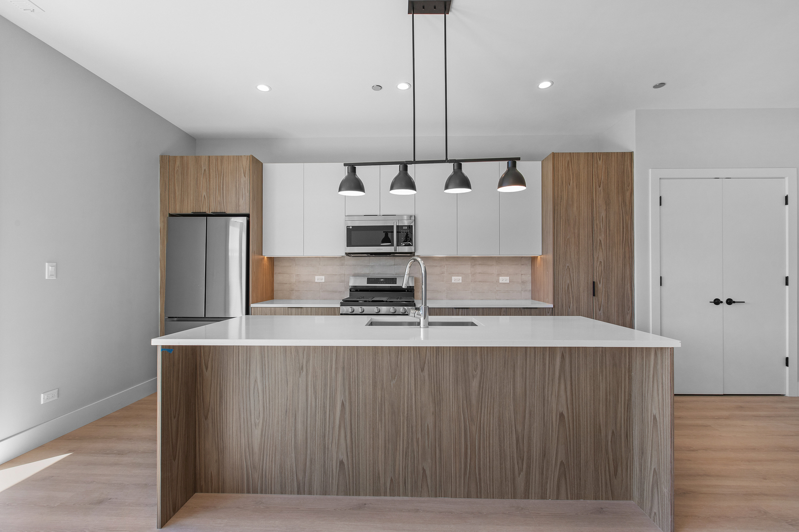 3953 West Dakin Street, Unit 405 Chicago, IL 60618 - Photo 4 of 21 a large kitchen with stainless steel appliances granite countertop a refrigerator a sink dishwasher a oven and a dining table with wooden floor