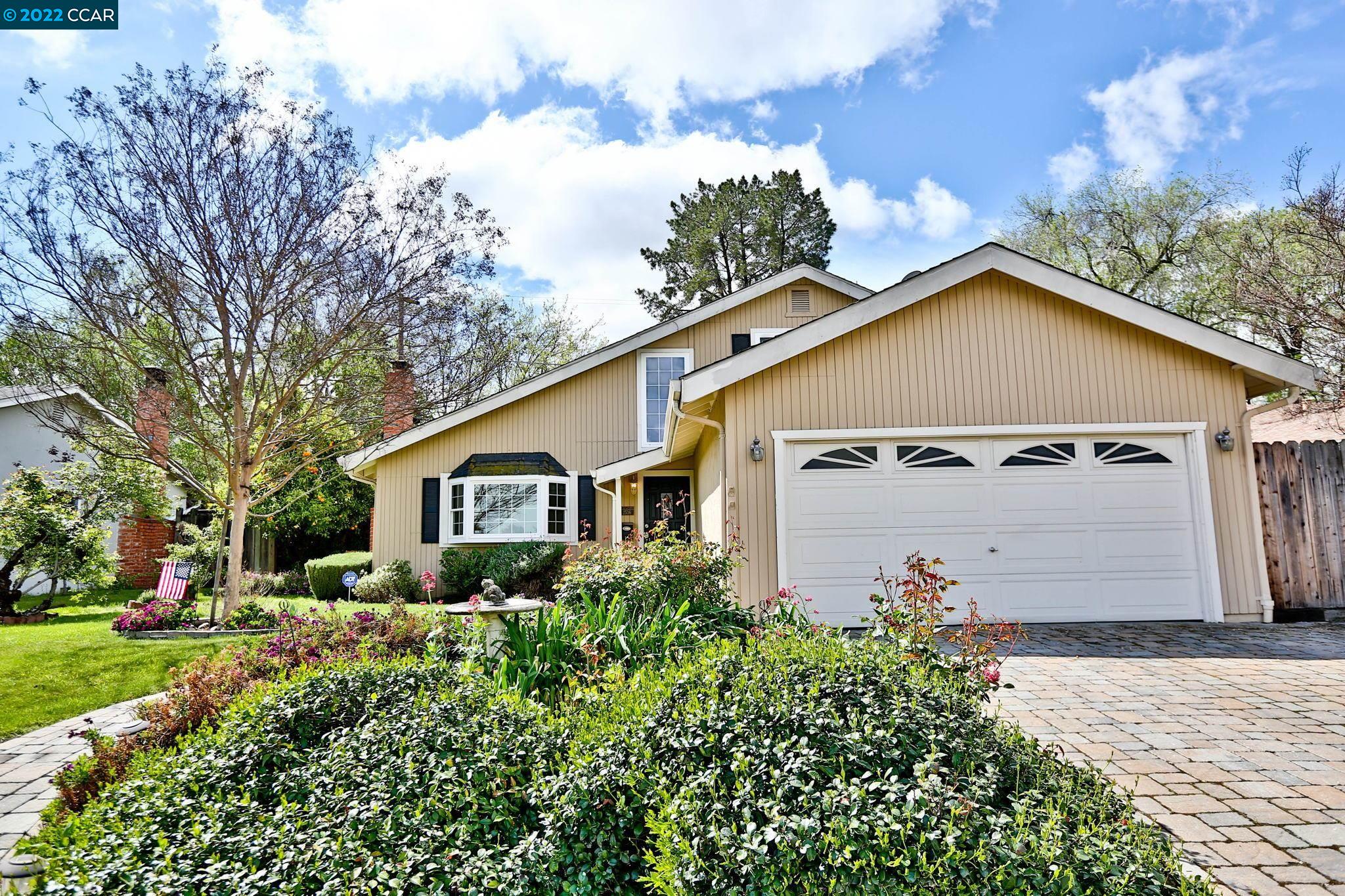 a view of a house with a yard plants and large tree