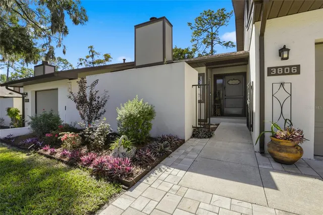 a front view of a house with lots of flowers and plants