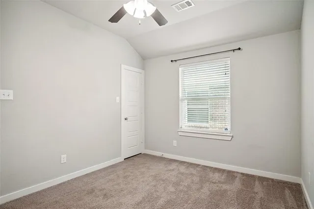 an empty room with a chandelier fan and windows