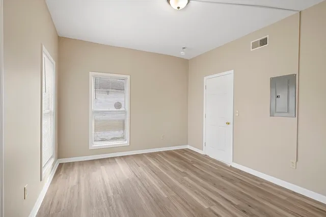 an empty room with wooden floor and windows