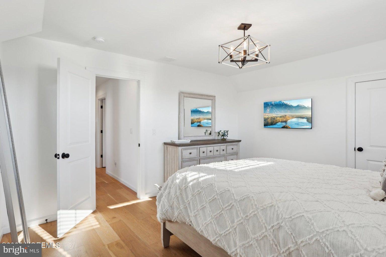 211 4th Street Beach Haven, NJ 08008 - Photo 23 of 48 a bedroom with a large bed chandelier and a window