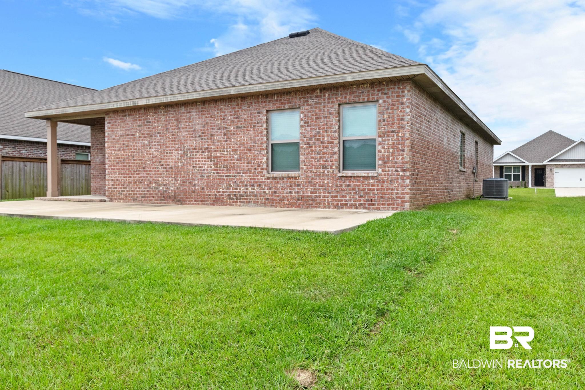 1710 Grouse Street Foley, AL 36535 - Photo 66 of 76 Expansive green lawn with a red brick exterior, concrete patio, covered porch area, and a visible HVAC unit