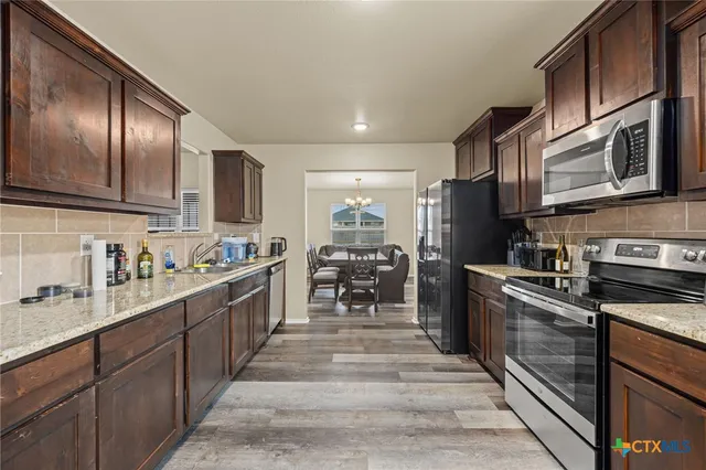 a large kitchen with stainless steel appliances wooden cabinets and a stove top oven