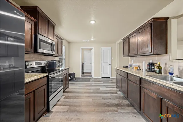 a kitchen with stainless steel appliances granite countertop a stove and cabinets