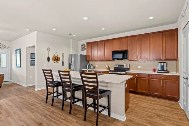 a kitchen with stainless steel appliances granite countertop wooden floor a dining table and chairs