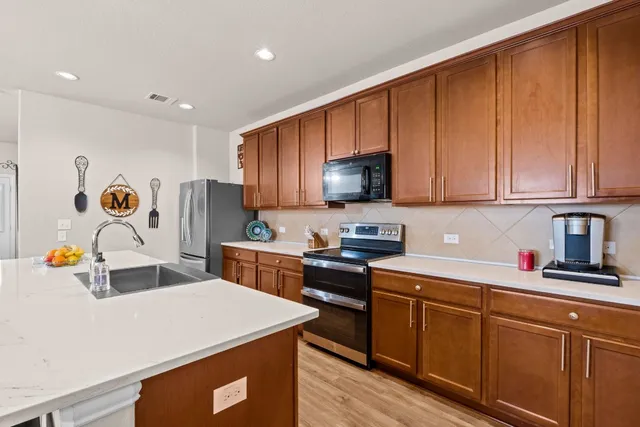 a kitchen with stainless steel appliances a sink a stove a refrigerator cabinets and a counter top space