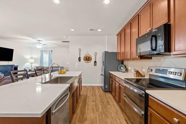 a kitchen with stainless steel appliances a sink a stove a refrigerator cabinets and a counter top space