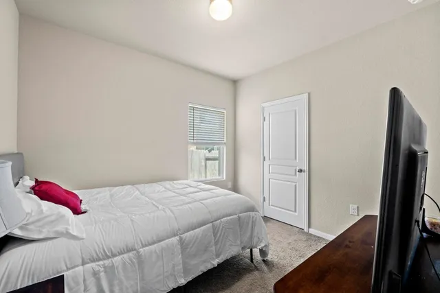 a bedroom with a bed and a flat tv screen on a dresser