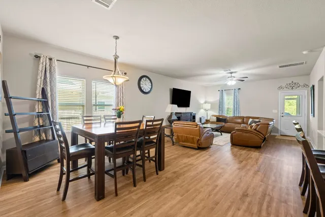 a living room with furniture kitchen view and a wooden floor