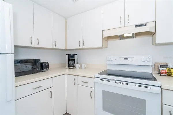a kitchen with white cabinets and white appliances