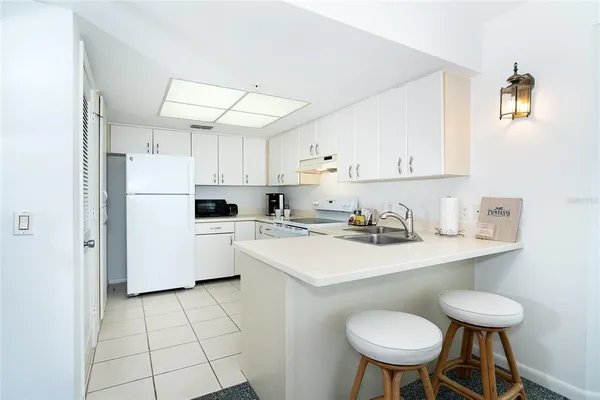a kitchen with a sink a stove a refrigerator and white cabinets
