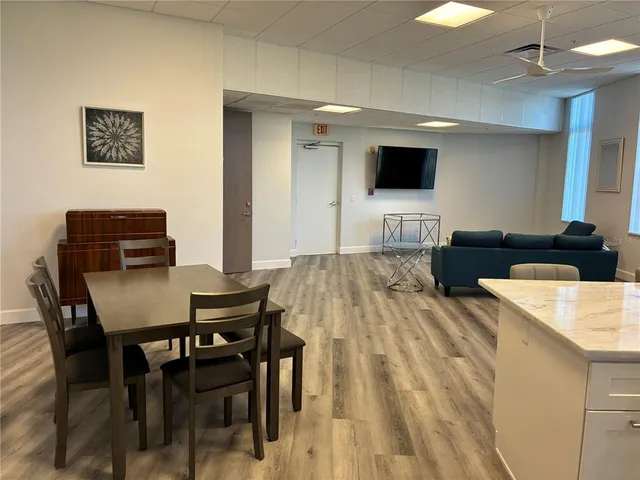 a kitchen with stainless steel appliances wooden floor and chairs