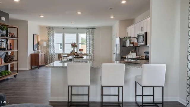 a kitchen with stainless steel appliances granite countertop a stove top oven a sink a dining table and chairs with wooden floor