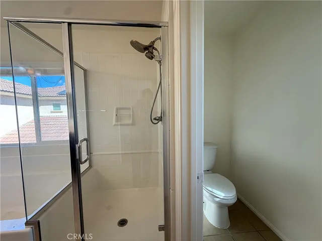 a bathroom with a shower a toilet and a glass door
