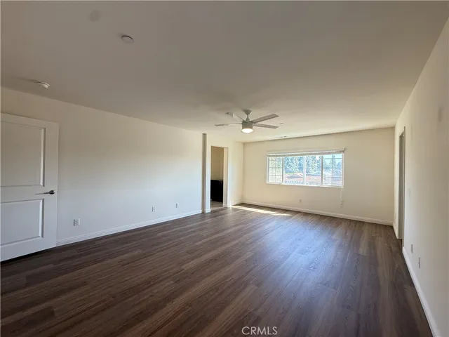 an empty room with wooden floor chandelier and windows