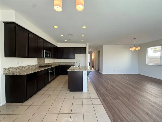 a kitchen with stainless steel appliances granite countertop a refrigerator a sink dishwasher a stove and a microwave oven on the blue kitchen countertops with wooden floor